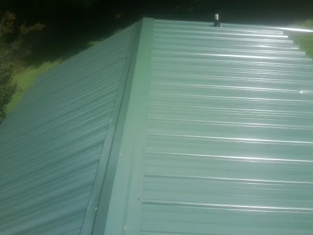 New green metal panels meeting at the ridge of a roof — Flat Roof Repair work by our crew in Landenberg