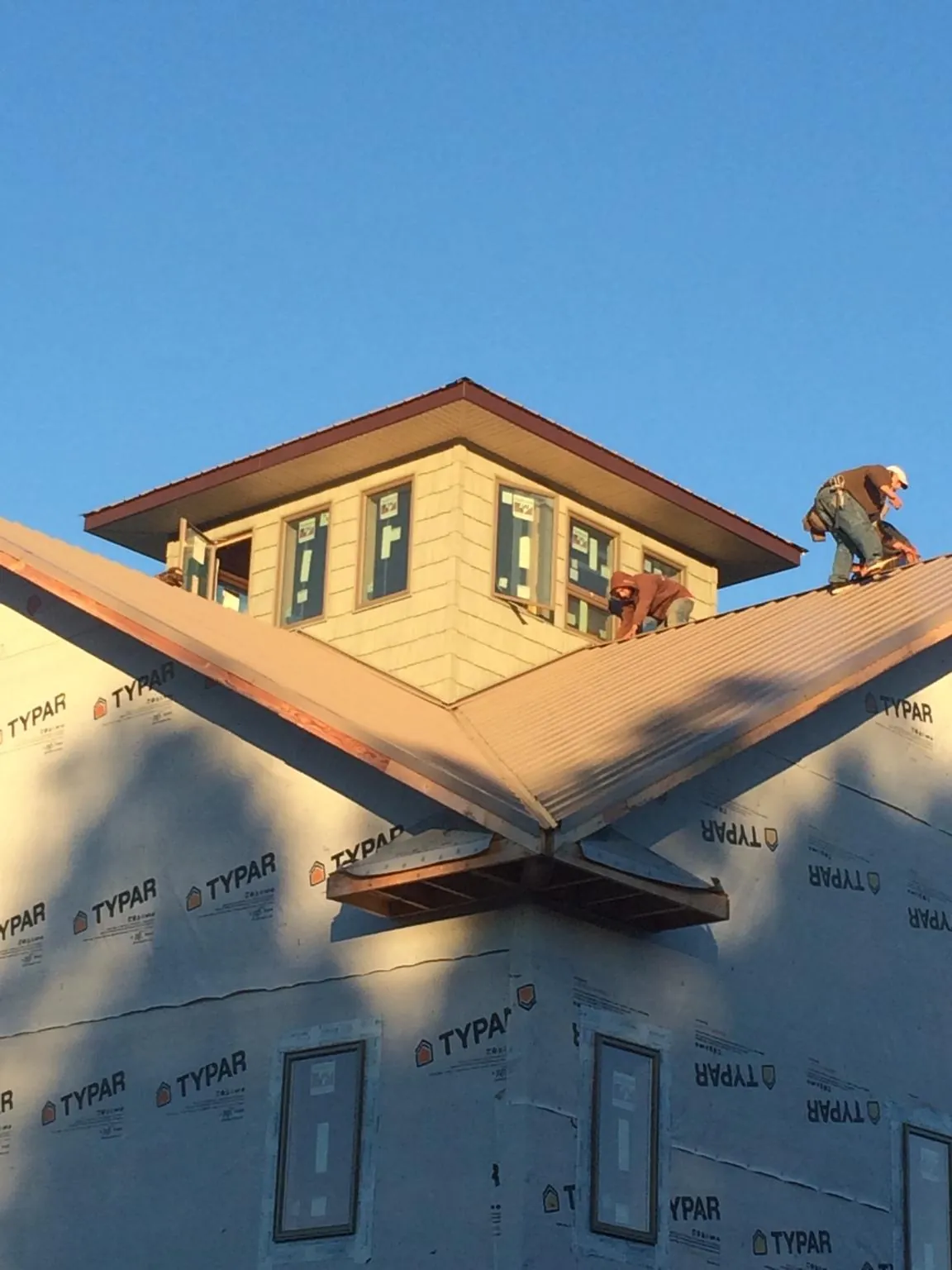 Roofers working around a rooftop cupola on a new metal roof at sunset — Roof Waterproofing in Landenberg by Roofing Brothers